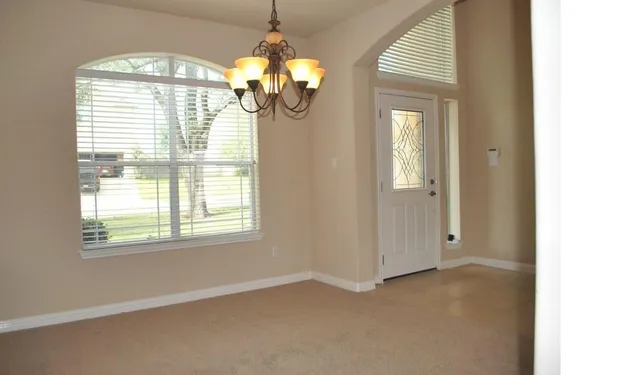 an empty room with windows and chandelier