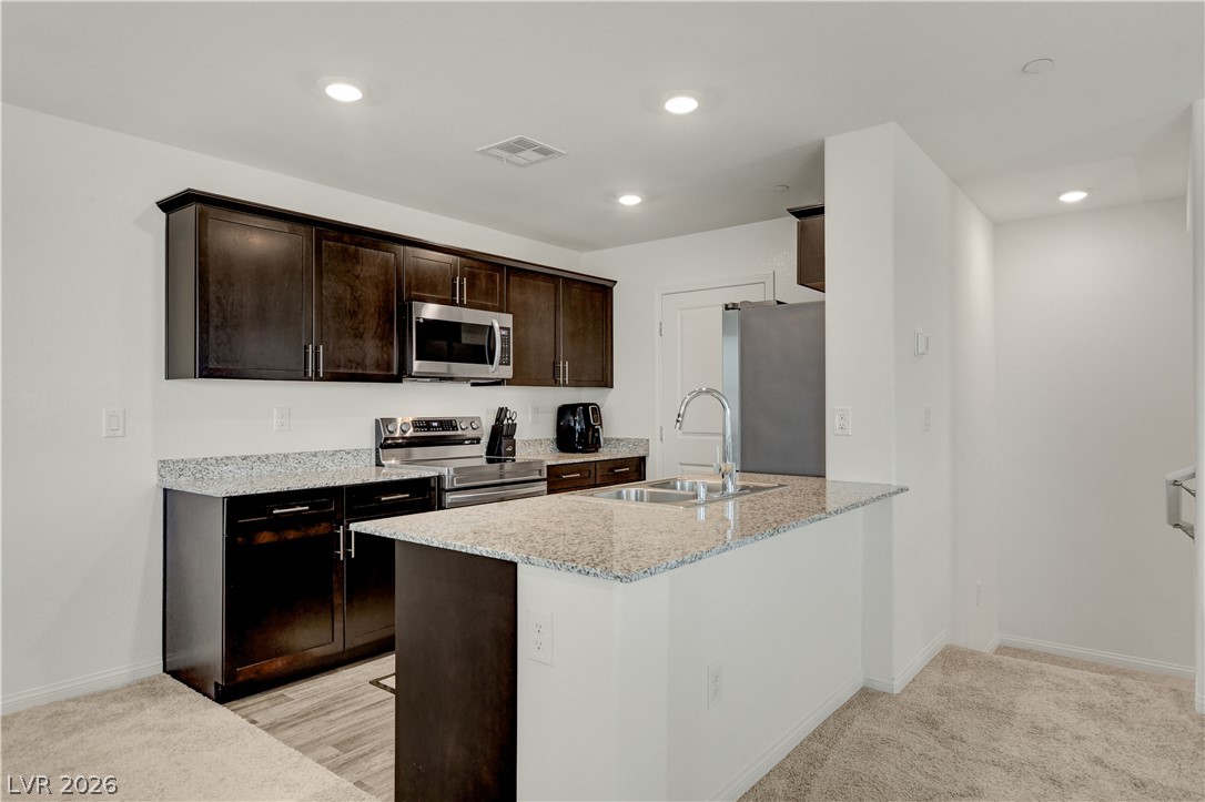 6924 Spicy Merlot Street North Las Vegas, NV 89086 - Photo 14 of 83 A well-appointed kitchen features dark wood cabinetry, granite countertops, and modern stainless steel appliances.