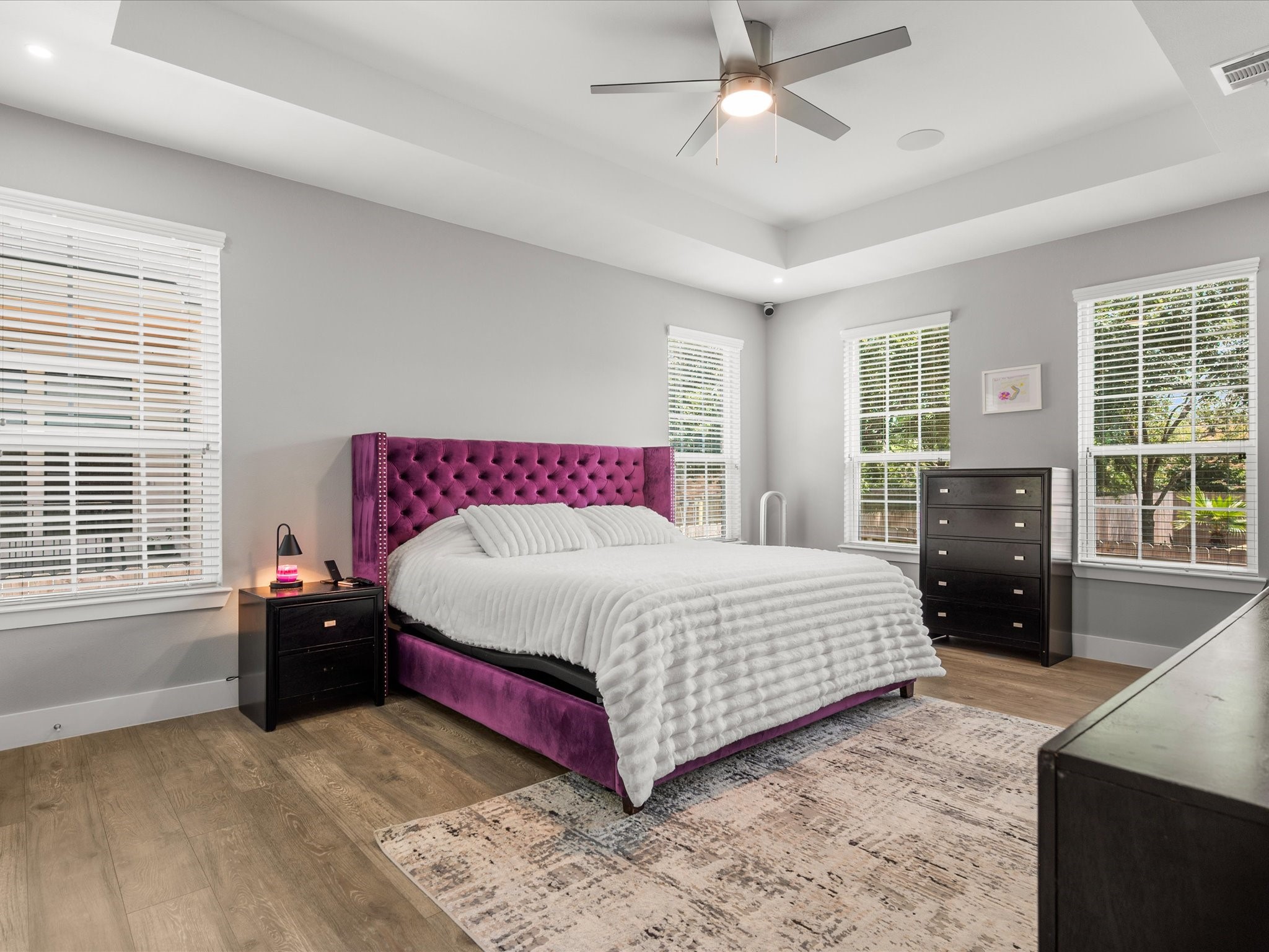 6207 Graff Net Court Spring, TX 77379 - Photo 22 of 48 The expansive primary suite offers a peaceful retreat with a dramatic tray ceiling, abundant windows, and warm wood flooring creating an inviting atmosphere.