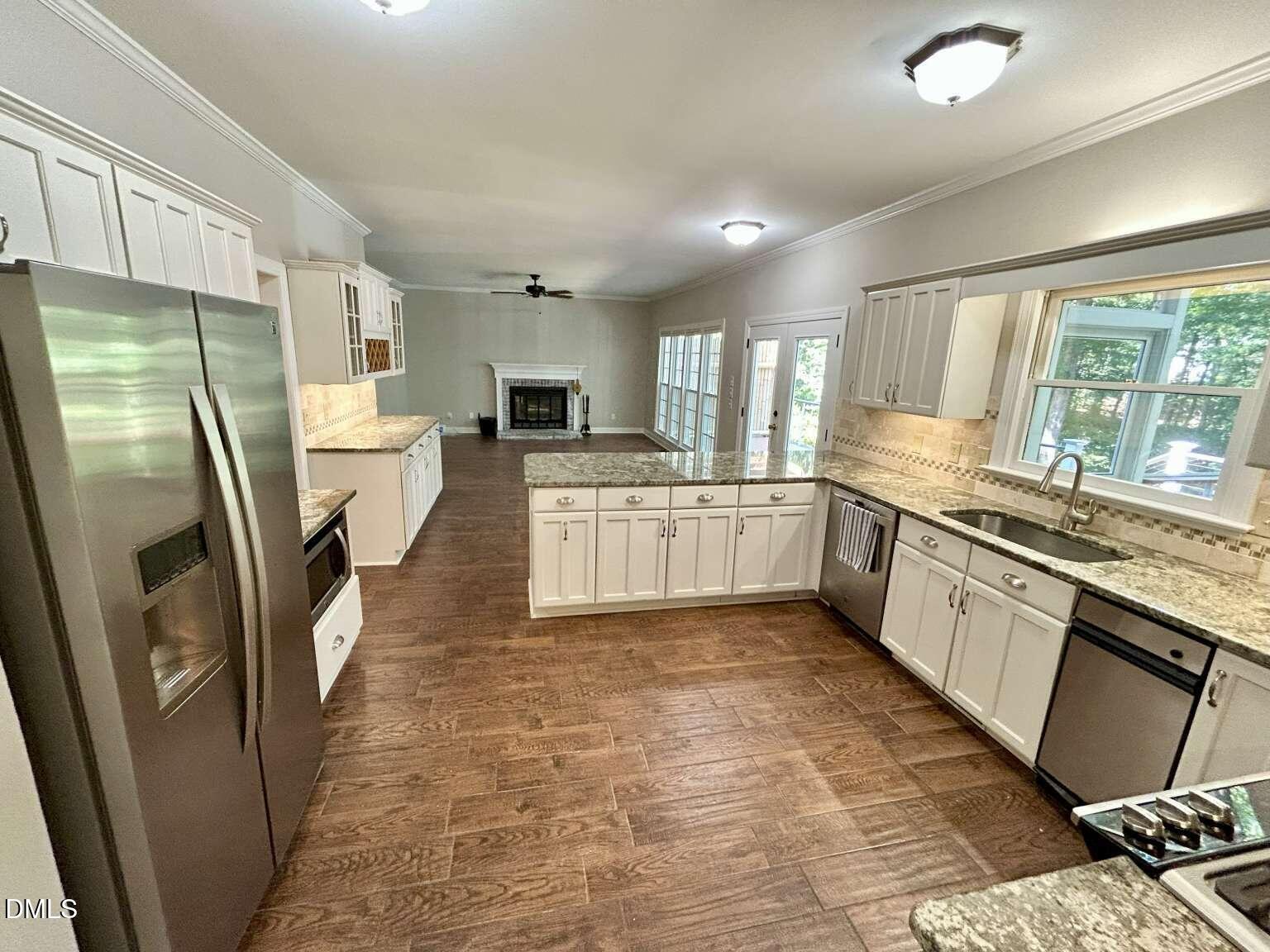 113 Ravenna Way Cary, NC 27513 - Photo 6 of 39 a large kitchen with a stove a refrigerator a sink dishwasher and white cabinets with wooden floor