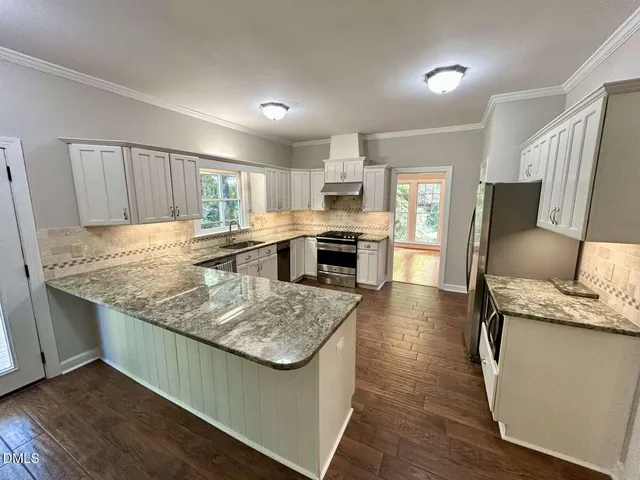 a kitchen with granite countertop a stove top oven a sink dishwasher a dining table and chairs with wooden floor