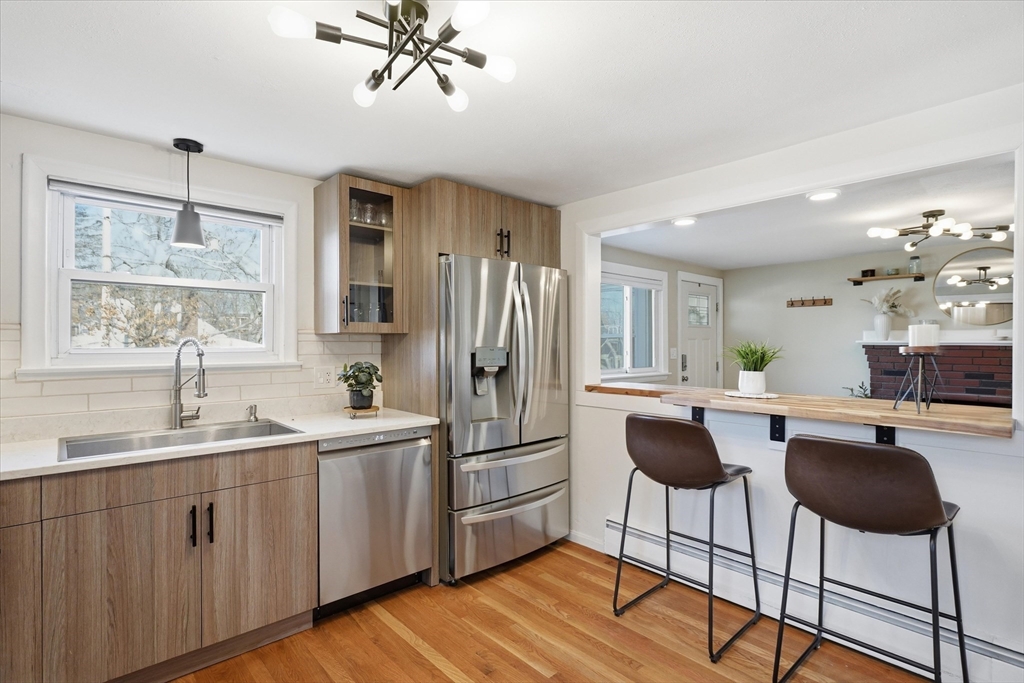 27 Garfield Avenue Saugus, MA 01906 - Photo 10 of 41 a kitchen with stainless steel appliances granite countertop a refrigerator a sink dishwasher a dining table and chairs with wooden floor