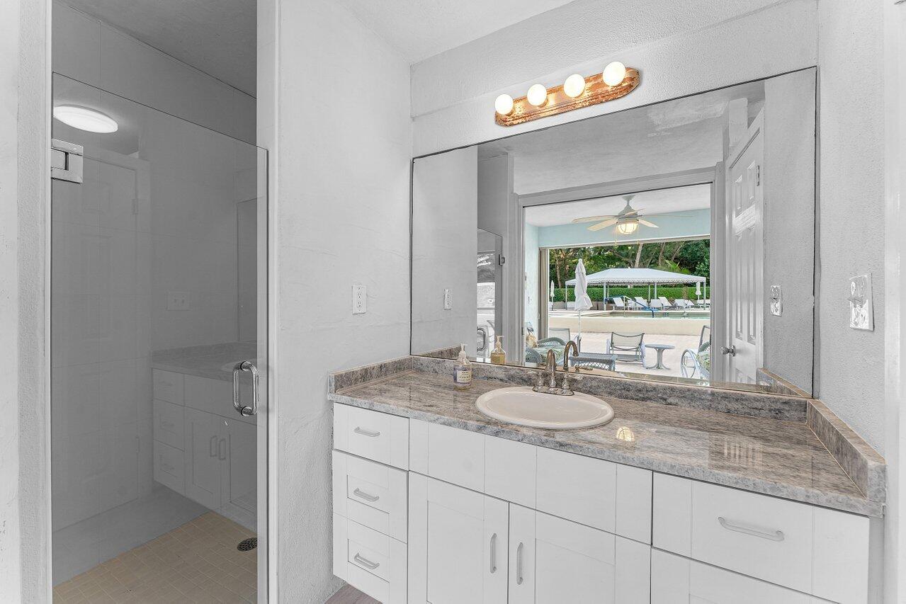 2774 South Ocean Boulevard, Unit 409 Palm Beach, FL 33480 - Photo 17 of 32 a bathroom with a granite countertop sink a mirror and a shower
