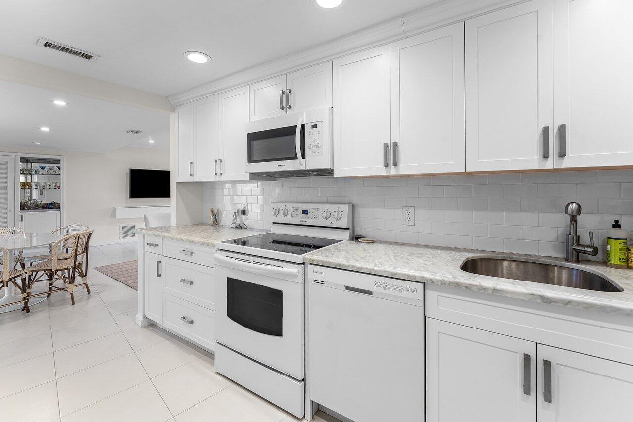 2774 South Ocean Boulevard, Unit 409 Palm Beach, FL 33480 - Photo 7 of 32 a kitchen with white cabinets sink and white appliances