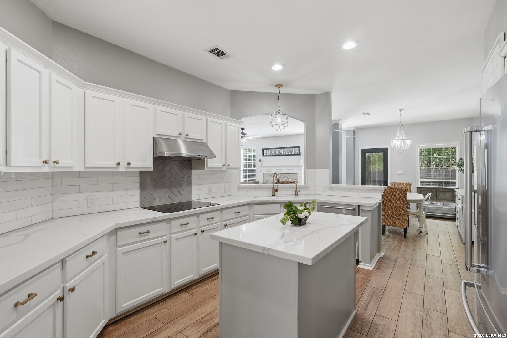 12703 Holly Cedar Helotes, TX 78023 - Photo 4 of 23 a kitchen with a sink dishwasher stove and white cabinets with wooden floor