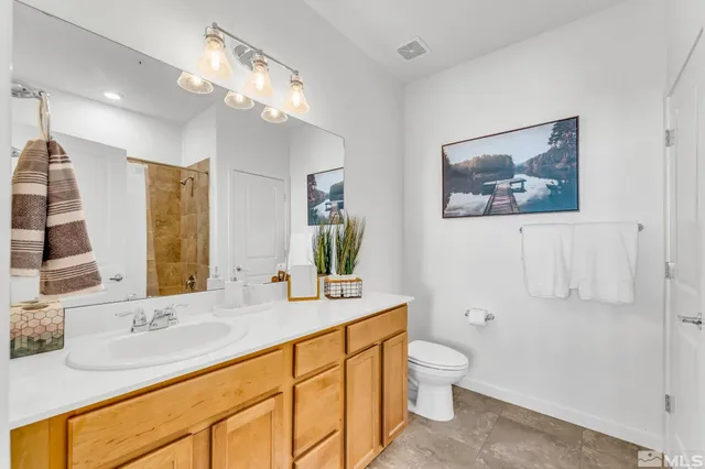 a bathroom with a granite countertop sink a toilet and a mirror