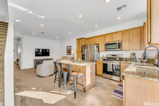 a kitchen with stainless steel appliances kitchen island granite countertop a sink refrigerator and microwave