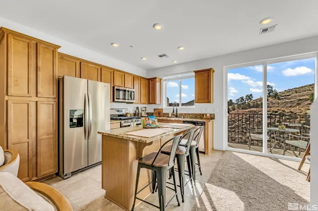 a kitchen with stainless steel appliances a refrigerator a stove a sink a dining table and chairs