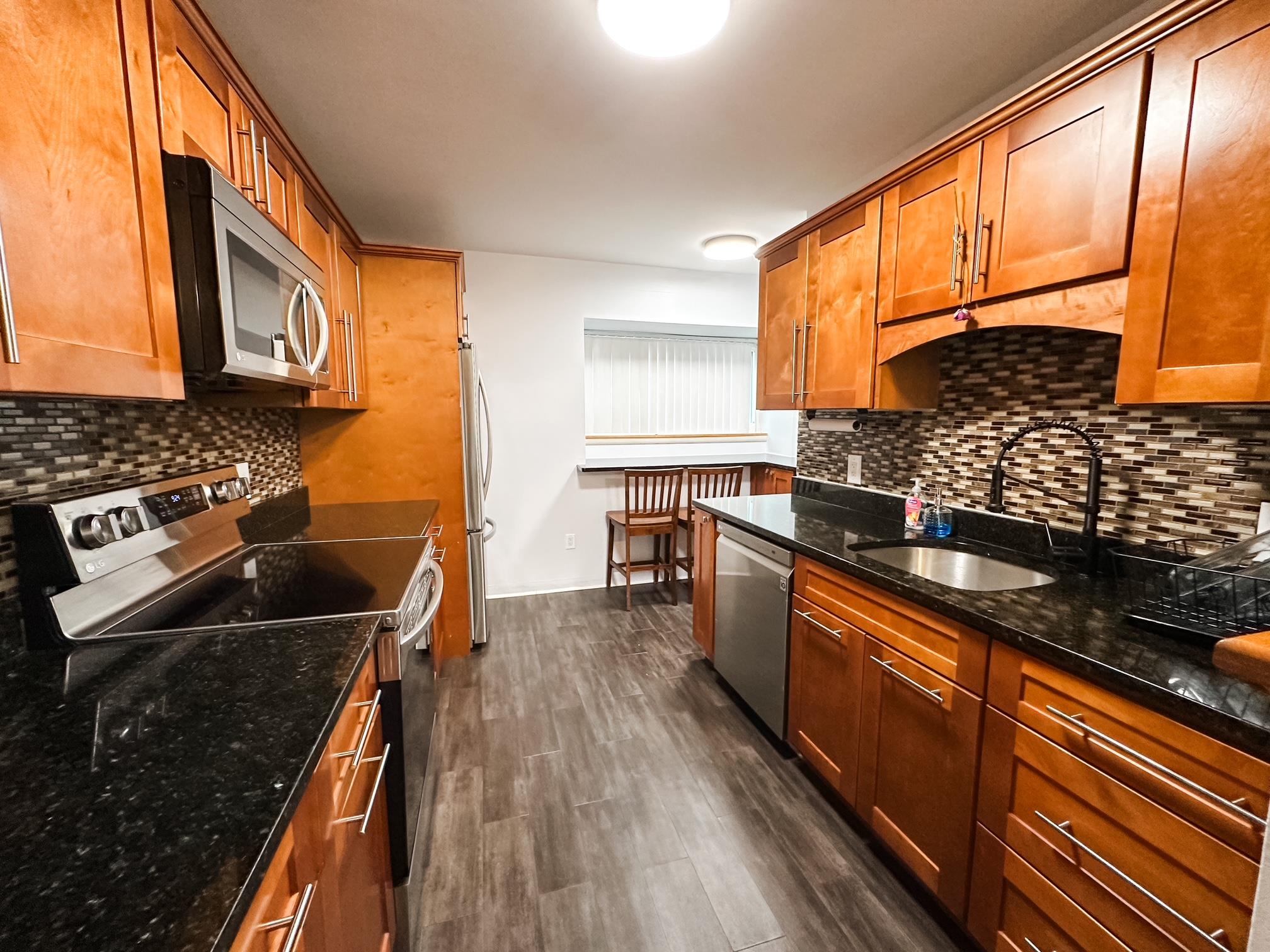 Kitchen with tasteful backsplash, stainless steel appliances, brown cabinets, and a sink