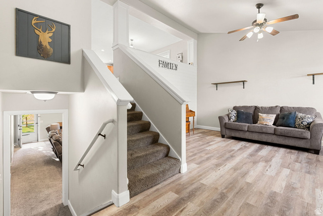 2485 South 1100th Street West Logan, UT 84321 - Photo 9 of 53 Open-concept living area featuring wood-finish flooring, a ceiling fan with integrated lighting, and a white staircase with carpeted treads