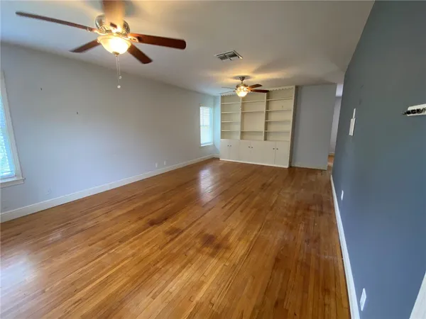 a view of empty room with wooden floor and fan