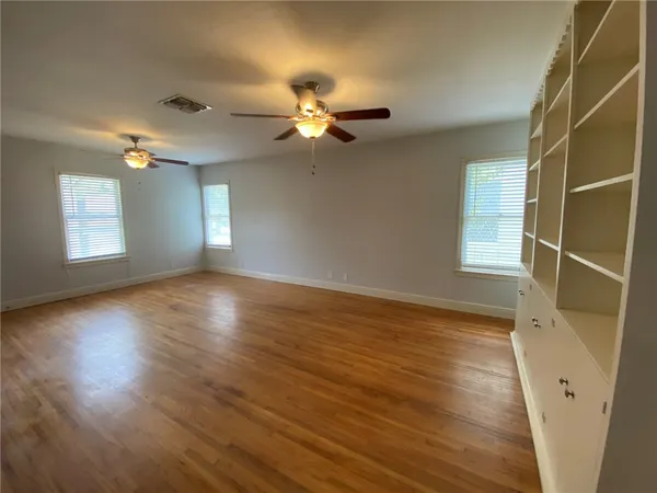 a view of an empty room with a window and wooden floor