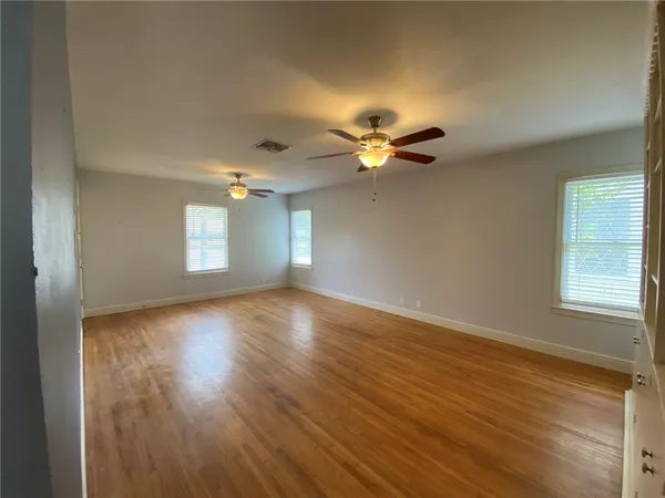 an empty room with wooden floor and windows