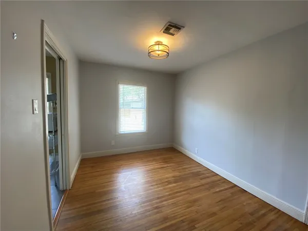 a view of an empty room with a window and wooden floor