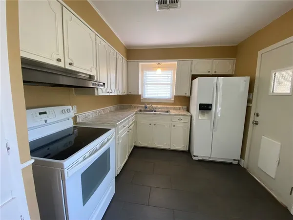 a kitchen with a sink a refrigerator and cabinets