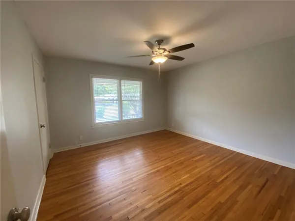 a view of empty room with wooden floor and fan