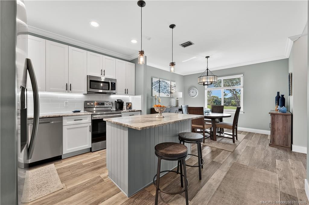 12463 Harbour Ridge Boulevard, Unit 26 Palm City, FL 34990 - Photo 13 of 34 a kitchen with kitchen island a appliances dining table and chairs