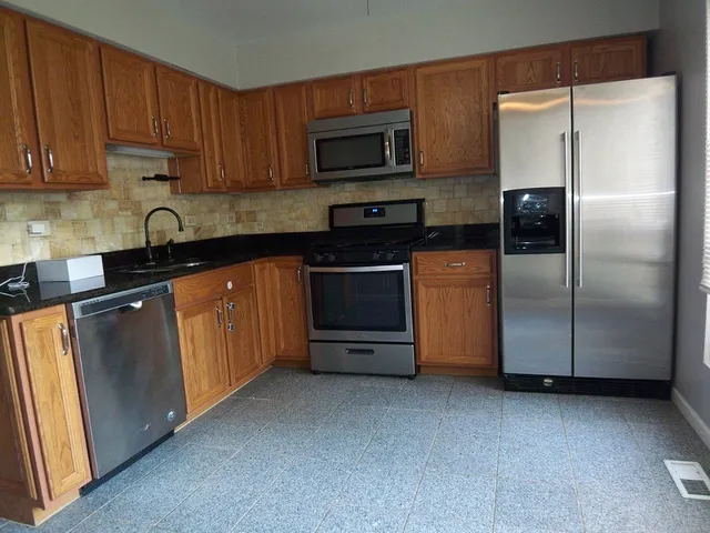 a kitchen with stainless steel appliances granite countertop a refrigerator a stove a sink and a microwave