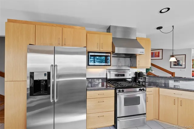 a kitchen with stainless steel appliances granite countertop a refrigerator a stove and a sink