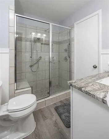 a bathroom with a granite countertop toilet a sink and shower