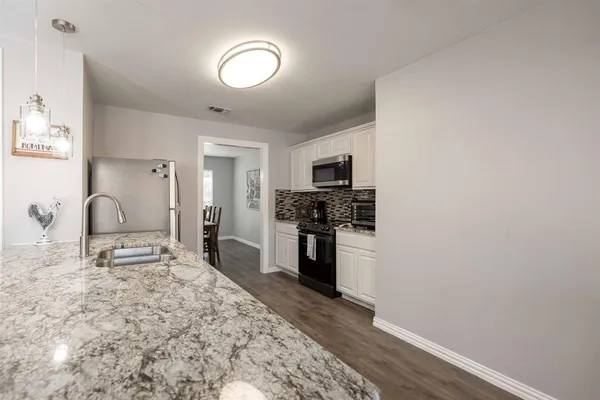 a kitchen with granite countertop a stove a sink and a refrigerator