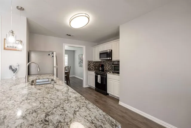 a kitchen with granite countertop a stove a sink and a refrigerator