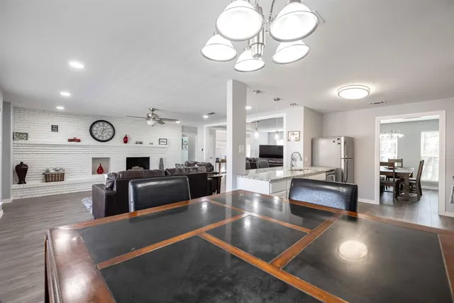 a kitchen with a sink dishwasher a dining table and chairs with wooden floor