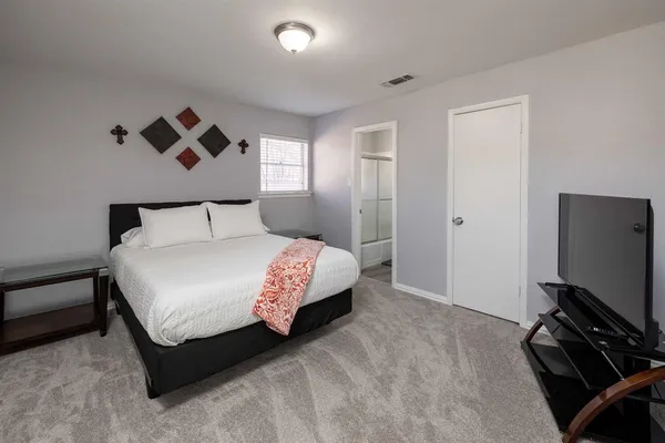 a bedroom with a bed and a flat tv screen on a dresser