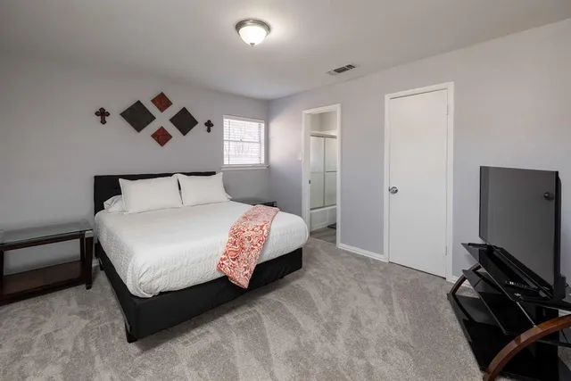 a bedroom with a bed and a flat tv screen on a dresser