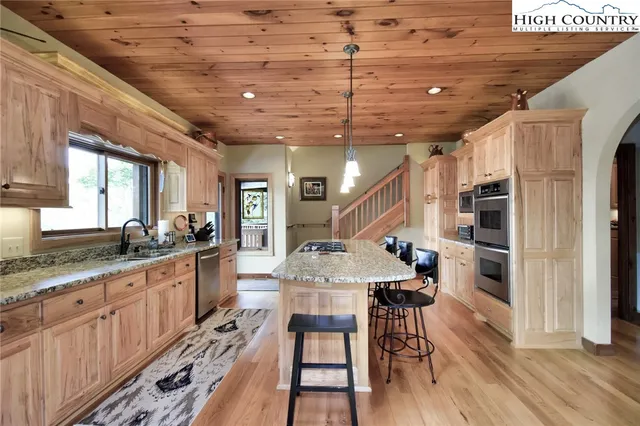 a kitchen with stainless steel appliances granite countertop a kitchen island a stove a table and chairs with wooden floor