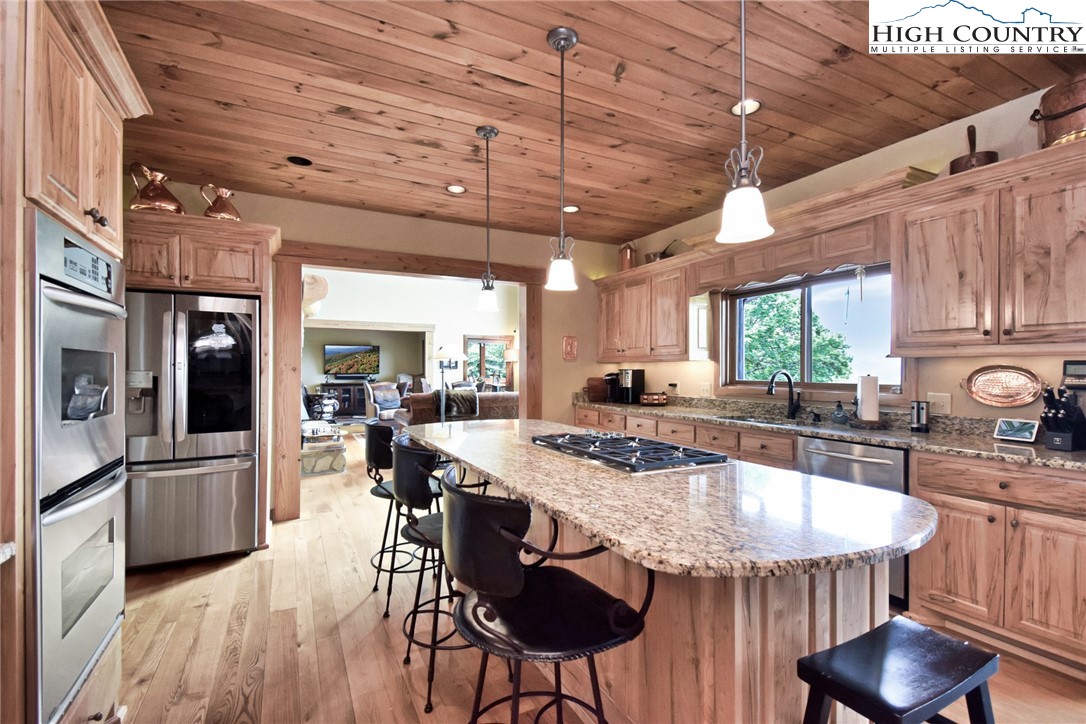 86 Tyneridge Road Banner Elk, NC 28604 - Photo 17 of 50 a kitchen with stainless steel appliances granite countertop a kitchen island a stove a table and chairs with wooden floor