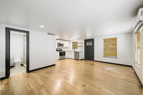 a view of an empty room with window and wooden floor