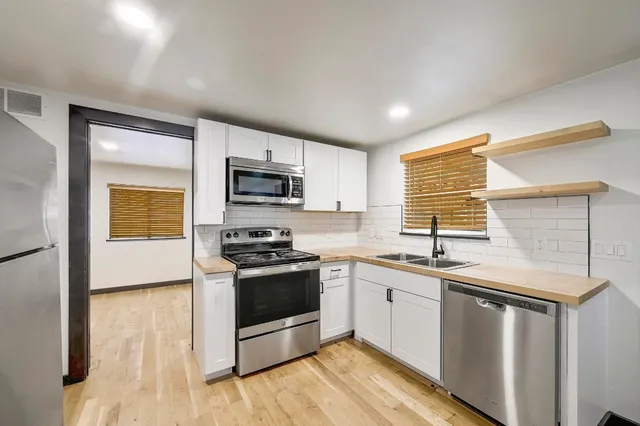 a kitchen with stainless steel appliances granite countertop a sink a stove a refrigerator cabinets and a window