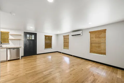 a view of an empty room with window and wooden floor