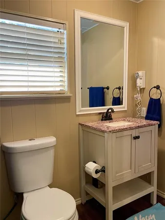 a bathroom with a granite countertop toilet a sink and a mirror