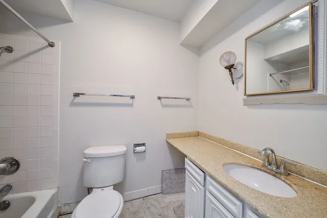 a bathroom with a granite countertop toilet sink and mirror
