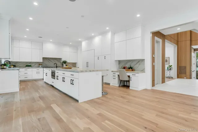 a large white kitchen with a large window and stainless steel appliances