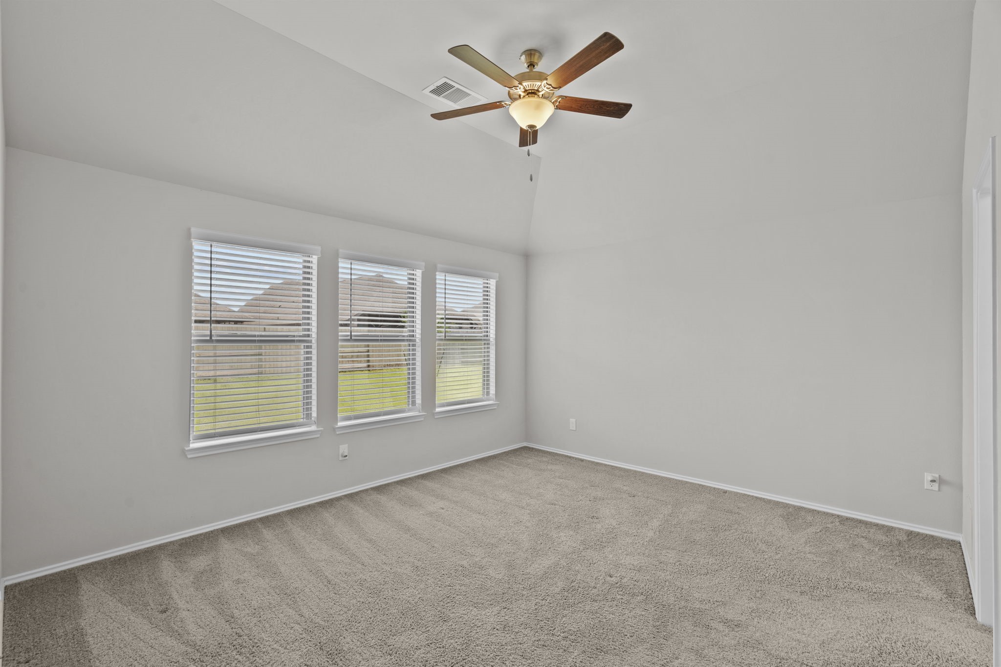 2011 Oak Leaf Court Manvel, TX 77578 - Photo 17 of 28 Bright and spacious room with a vaulted ceiling, neutral walls, and plush carpet. Features a ceiling fan and three large windows overlooking a grassy backyard.