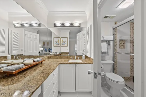 a bathroom with a granite countertop sink a toilet a mirror and shower