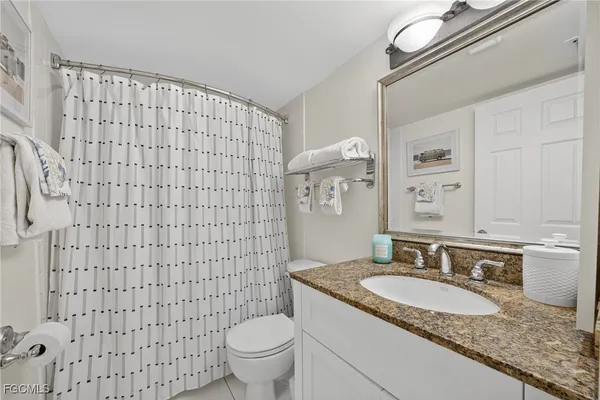 a bathroom with a granite countertop toilet sink and mirror