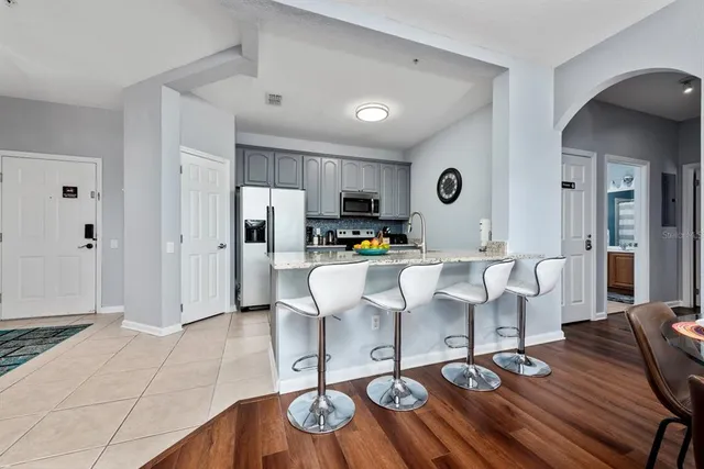 a living room with couches a coffee table and kitchen view with wooden floor