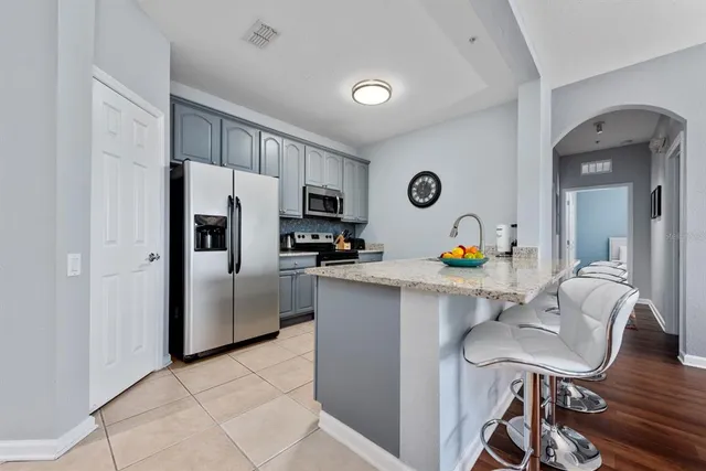 a kitchen with stainless steel appliances a refrigerator a stove a dining table and chairs with wooden floor