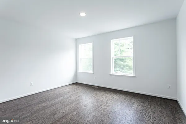 an empty room with wooden floor and window