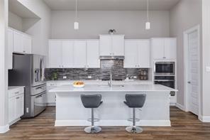 601 C-Bar Ranch Trail, Unit 51 Cedar Park, TX 78613 - Photo 12 of 33 Kitchen featuring light countertops, a kitchen bar, white cabinetry, stainless steel refrigerator with ice dispenser, and a center island with sink