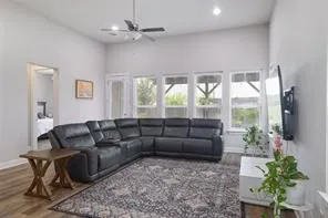 a living room with furniture potted plant floor to ceiling windows and a flat screen tv