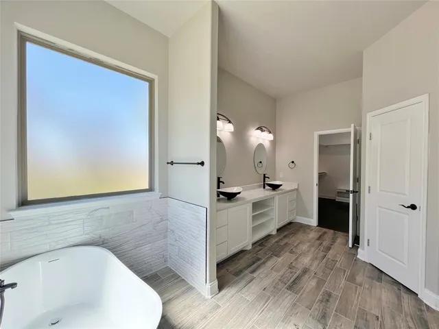 a large white bathroom with a double vanity sink a mirror and a bathtub