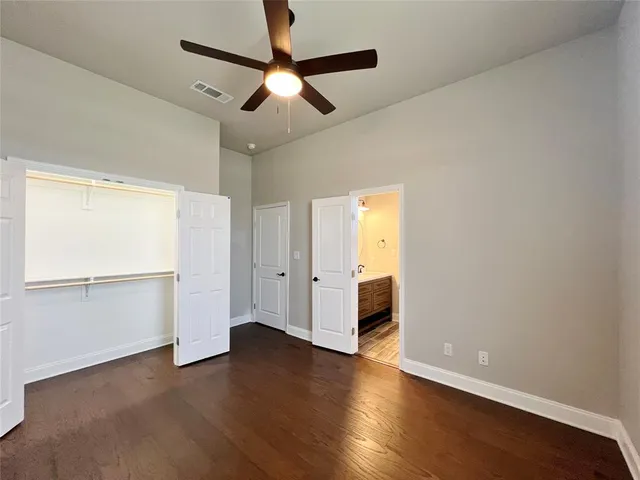 an empty room with wooden floor cabinet and windows
