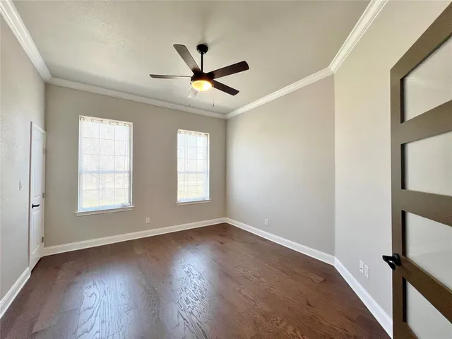 a view of empty room with wooden floor and fan
