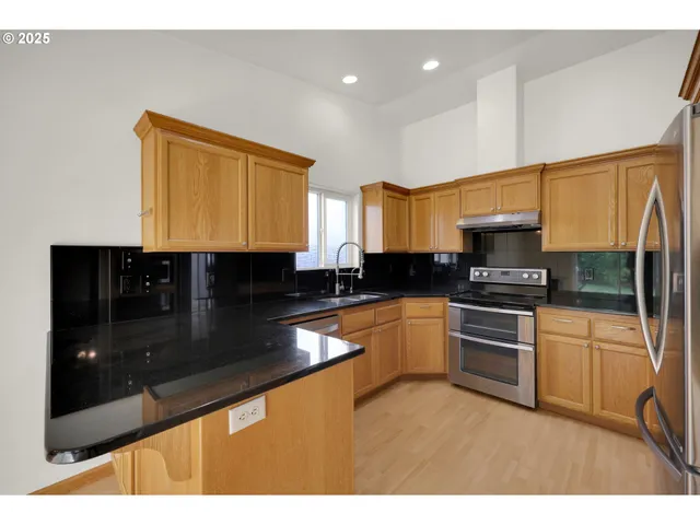 a kitchen with stainless steel appliances granite countertop a stove a sink and a microwave
