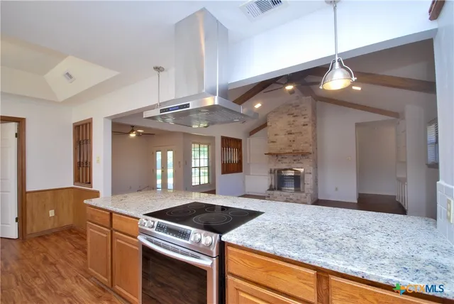 a kitchen with stainless steel appliances a refrigerator a sink a stove and white cabinets with wooden floor